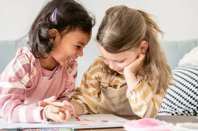 two children colouring and laughing